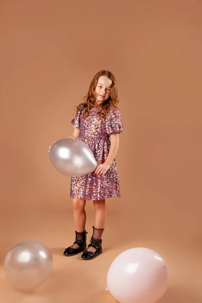 Menina em um vestido com lantejoulas para uma festa segurando um balão em ele — Fotografia de Stock