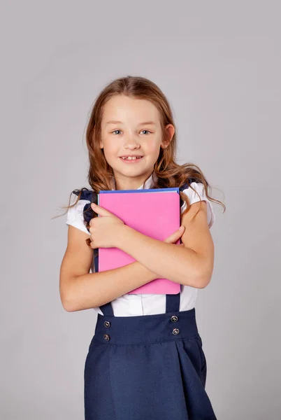 Colegiala sostiene una pila de cuadernos y sonrisas — Foto de Stock