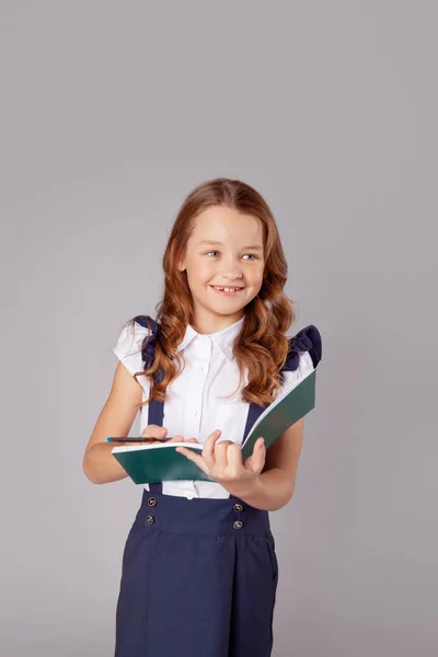 Lächelndes Mädchen schreibt etwas in ein offenes Notizbuch — Stockfoto