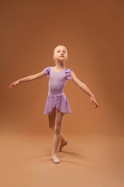 Menina em um vestido roxo mostra elementos de balé — Fotografia de Stock