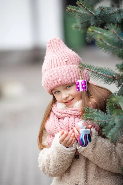 girl decorate a street tree with Christmas toys