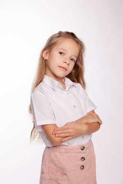 Sevimli kız sakince kameraya bakıyor, kollarını kavuşturuyor.