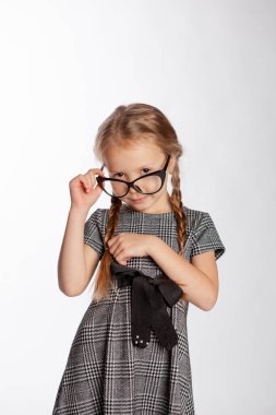 Katı gri elbiseli kız burnuna gözlük takıyor.