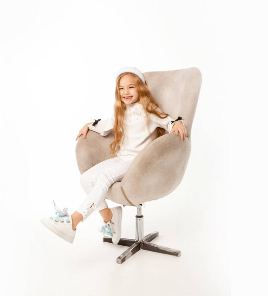 Девушка с длинными волосами, одетая в белую одежду, сидит в кресле
