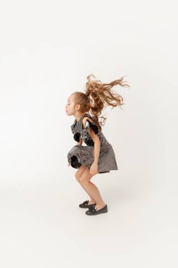 Küçük kız beyaz bir arka planda zıplıyor.