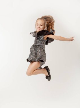 Küçük kız beyaz bir arka planda zıplıyor.