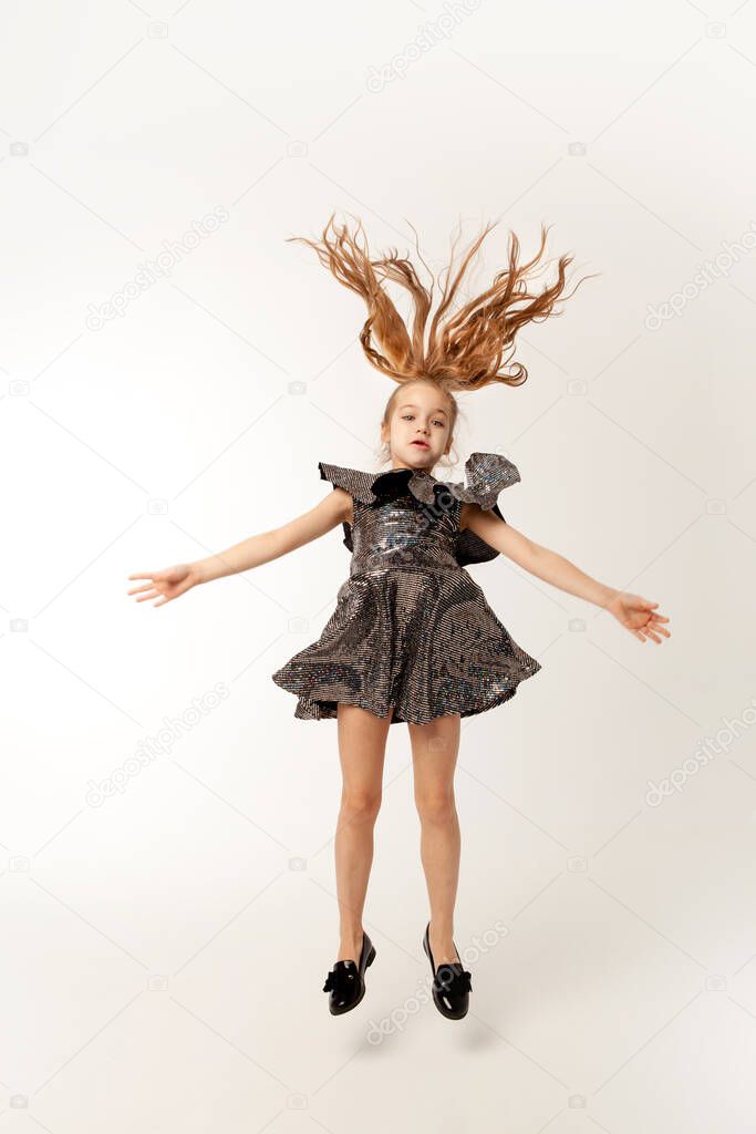 little girl bounces up on a white background