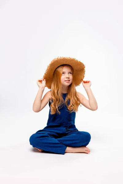 Menina Ruiva Sentado Macacão Azul Chapéu Palha Pernas Cruzadas — Fotografia de Stock