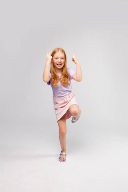 Kızıl saçlı, uzun saçlı, günlük kıyafetleri olan bir kız.)