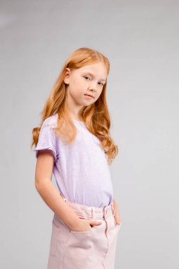 Kızıl saçlı, uzun saçlı, günlük kıyafetli bir kız. 