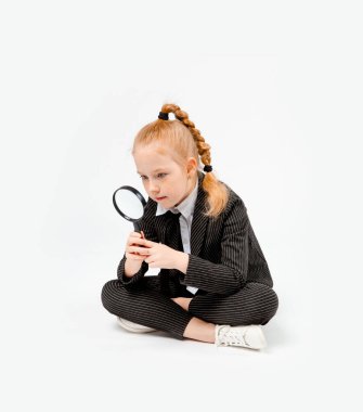 girl in a business black suit sits cross-legged and looks in surprise through a magnifying glass. clipart