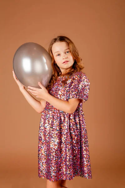 girl in a party dress holding a balloon in her hands