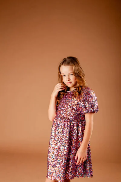 pensive girl in sequin dress touches hair