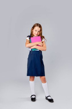 Okul üniformalı kız okul defterlerini elinde tutuyor.