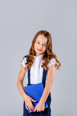 Okul üniformalı kız okul defterlerini elinde tutuyor.