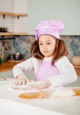 Mutfaktaki kız hamur yoğuruyor.