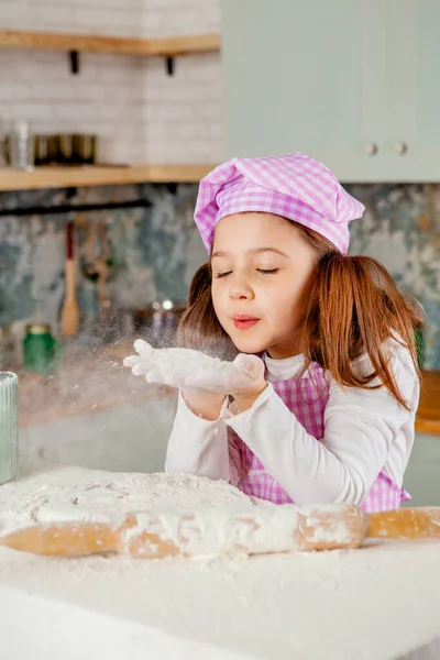 Girl in the kitchen kneads dough