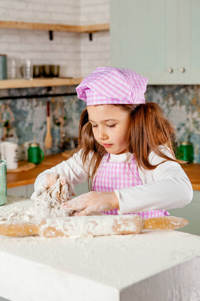 Girl in the kitchen kneads dough