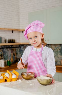Mutfaktaki küçük kız hamur yoğuruyor. 