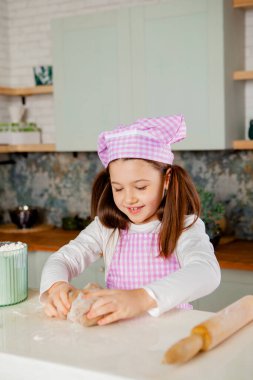 Mutfakta gülümseyen kız hamur yoğurur.