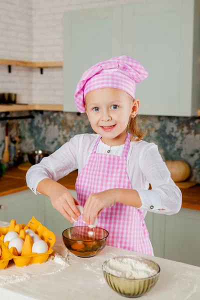 Girl in a chef\'s hat and apron kneads dough
