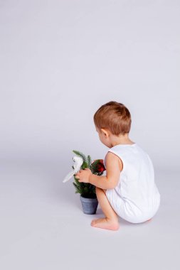 Bebek Noel ağacını Noel oyuncağıyla süslemeye çalışıyor.