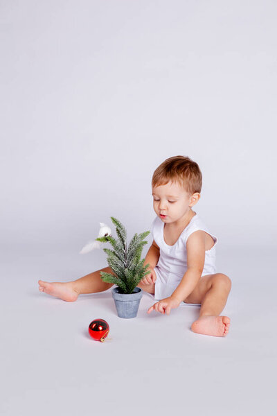 ребенок пытается украсить елку рождественской игрушкой
