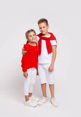 Erkek kardeş kız kardeşe sarılır. Fotoğraf beyaz bir stüdyoda çekildi.