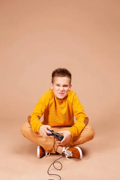 자녀는 조이스틱을 사용하여 컴퓨터 게임이나 게임을 감정적으로 합니다 소년은 베이지 — 스톡 사진
