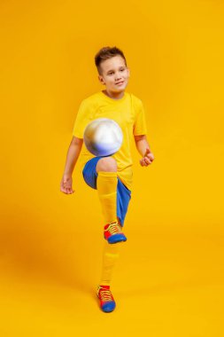 Çocuk stüdyoda futbol oynuyor.