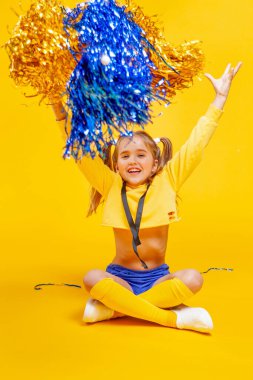 cheerleader girl in a yellow tank and blue shorts throws up pompons clipart