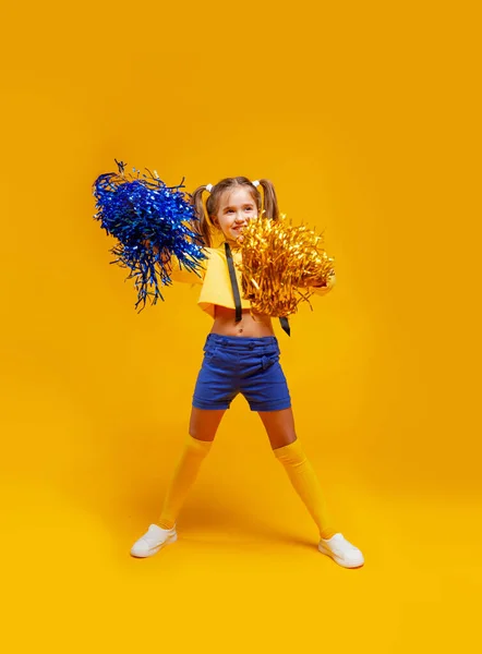 cheerleader girl in a yellow tank top and blue shorts is dancing with pompons in her hands