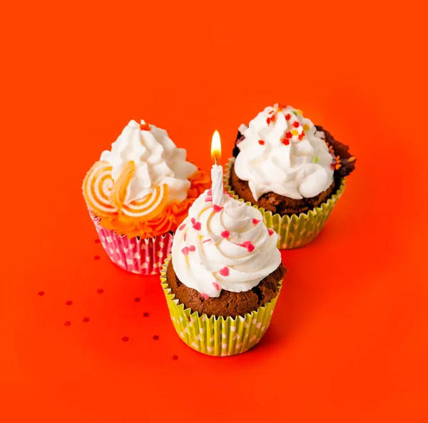 Tre Cupcakes Med Tänd Ljus Grädde Orange Bakgrund — Stockfoto