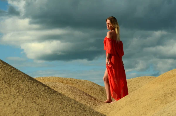 Menina em um vestido vermelho na areia — Fotografia de Stock