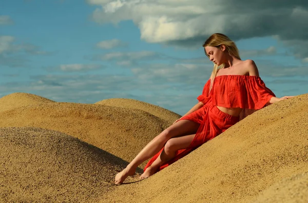Flicka i en röd klänning i sand — Stockfoto