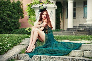 Uzun bacaklı yeşil giysili basamaklarında oturan bir kadınla.