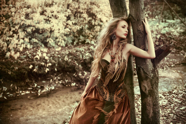 Fantastic woman in the autumn forest with flying hair.
