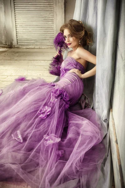 Retrato de uma mulher elegante em um vestido lilás com um ventilador . — Fotografia de Stock