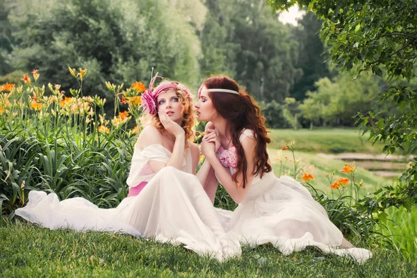 Lovely bridesmaids sitting on the grass. — Stock Photo, Image