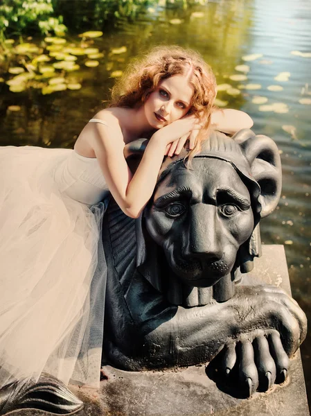 Gyönyörű lány ül egy oroszlán szobor. Stock Kép