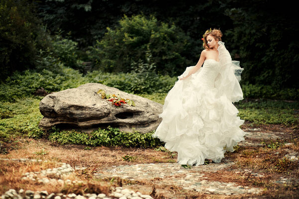 Gorgeous bride in a lush white dress is dancing in nature.