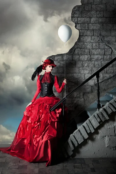Frau in rotem historischen Kleid hält weißen Luftball in der Hand. — Stockfoto