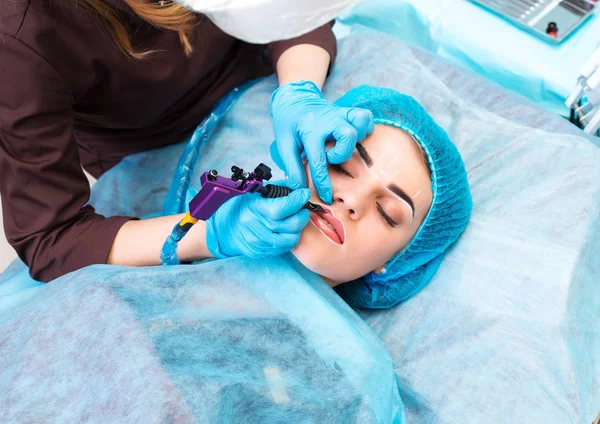 Косметолог делает постоянный макияж на женском лице — стоковое фото