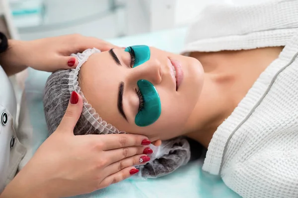 Cosmetische procedure, het gezicht van de dames met groene vlokken onder de ogen. — Stockfoto