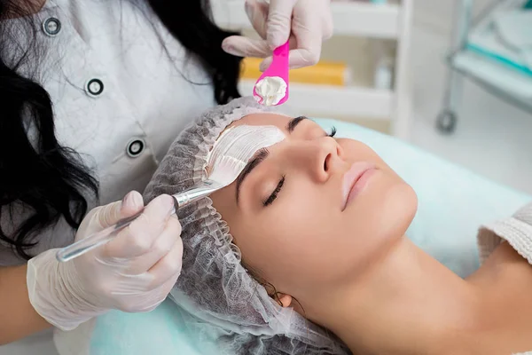 Mooie vrouw met gezichtsmasker bij schoonheidssalon. — Stockfoto