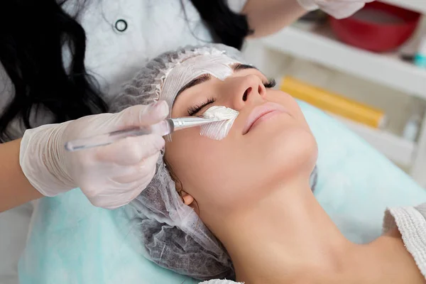 Mooie vrouw met gezichtsmasker bij schoonheidssalon. — Stockfoto