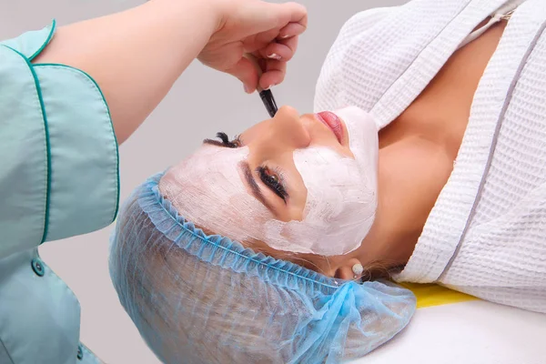 Kvinna med lera ansiktsmask i beauty spa. — Stockfoto
