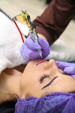Kadının yüzünde kalıcı makyaj yapma güzellik uzmanı