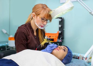 Kadının yüzünde kalıcı makyaj yapma güzellik uzmanı