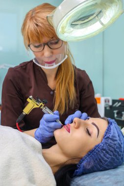 Kadının yüzünde kalıcı makyaj yapma güzellik uzmanı